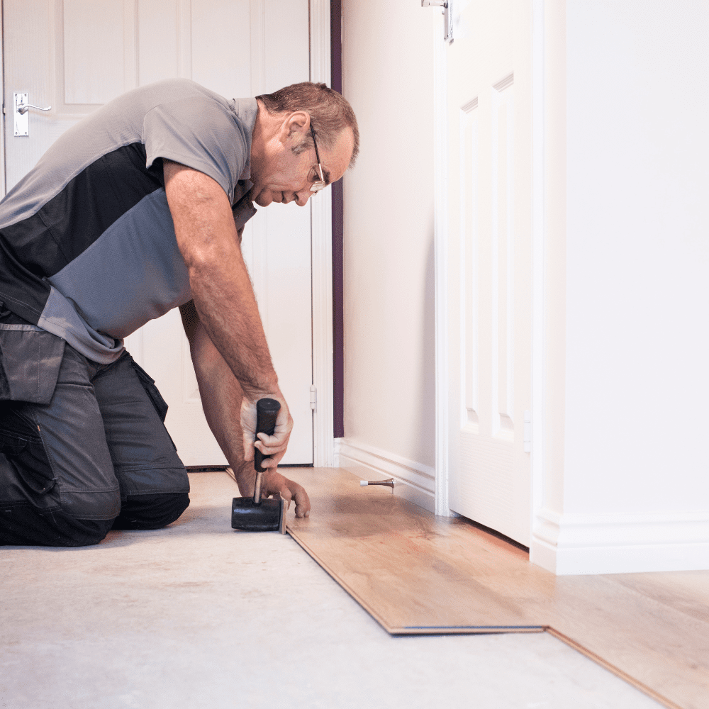 Fitter installing click vinyl flooring using a rubber mallet.